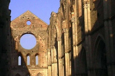 In einem der bezauberndsten Szenarien der Toskana befinden sich die Ruinen der Abtei San Galgano mit ihrem Fußboden mit Margariten und ihrem Sternendach, und die Rotunde vom Montesiepi, mit dem Heiligen Schwert im Felsen.